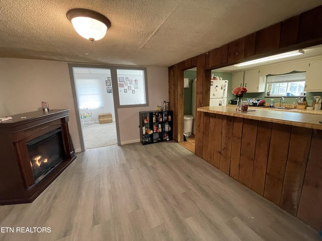 kitchen with white fridge, sink, light wood-type flooring, and a textured ceiling