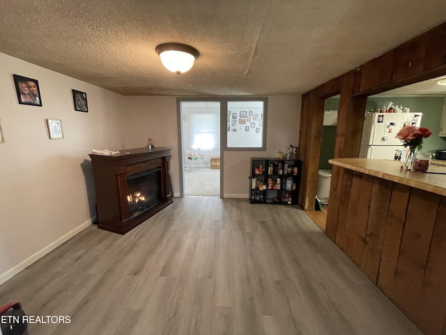 living room featuring light hardwood / wood-style floors, a textured ceiling, and bar area