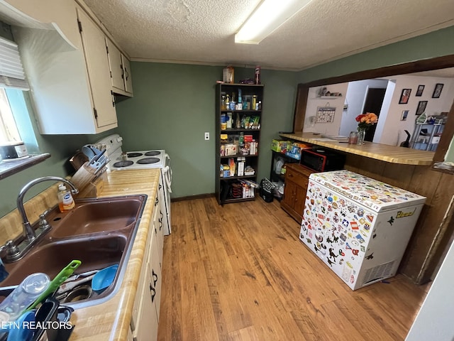 kitchen with white cabinetry, sink, white electric range, a textured ceiling, and light wood-type flooring