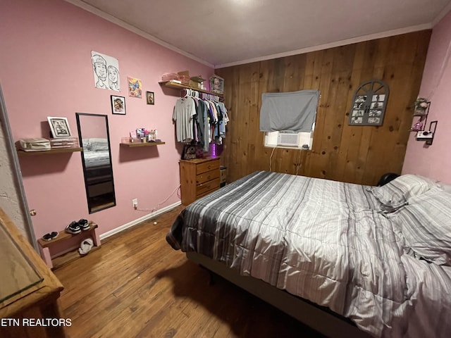 bedroom with crown molding, wooden walls, cooling unit, and wood-type flooring