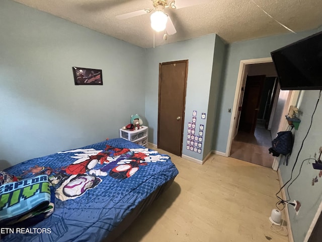 bedroom featuring ceiling fan, wood-type flooring, and a textured ceiling