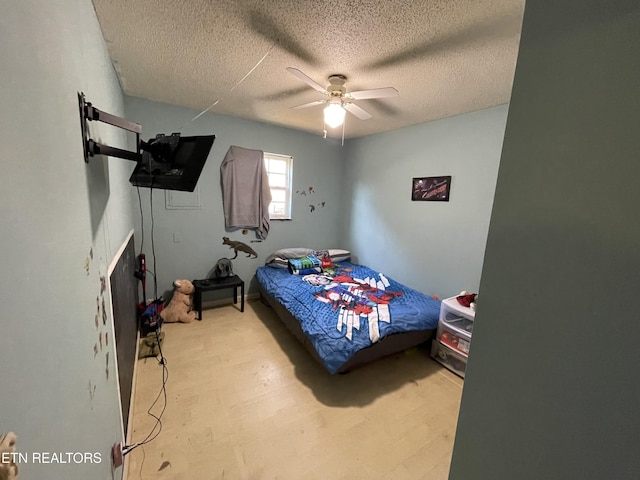 bedroom with ceiling fan, light hardwood / wood-style floors, and a textured ceiling