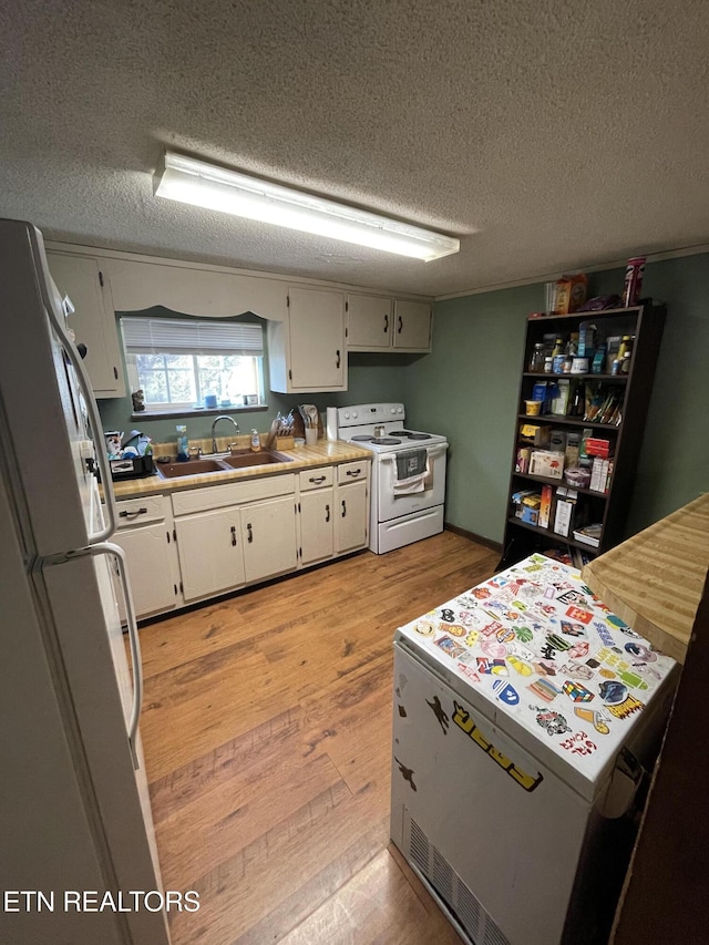 kitchen featuring light hardwood / wood-style floors, sink, white appliances, and a textured ceiling