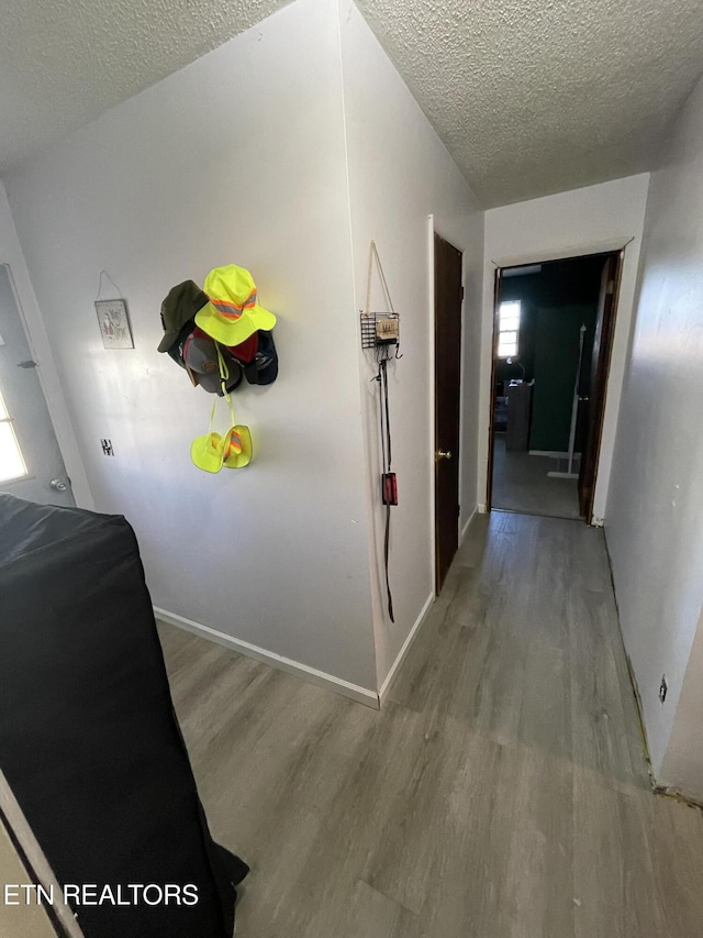 corridor with light hardwood / wood-style flooring and a textured ceiling