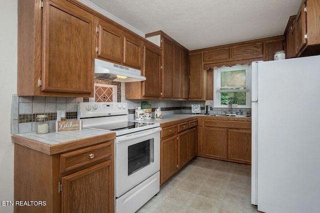 kitchen featuring tile counters, white appliances, sink, and tasteful backsplash