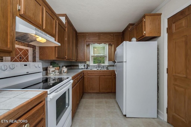 kitchen with white appliances, tile countertops, backsplash, and sink