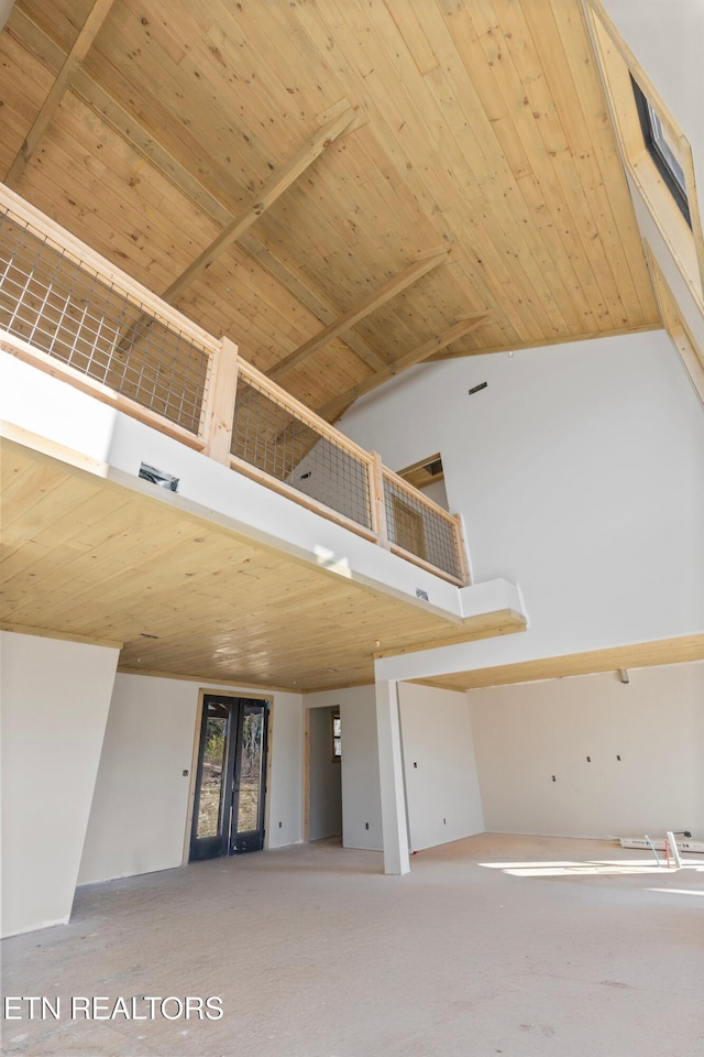 unfurnished living room featuring wood ceiling, a high ceiling, and french doors