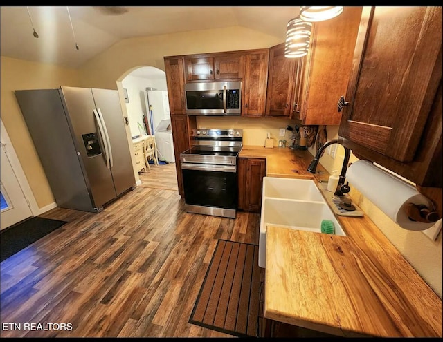 kitchen featuring appliances with stainless steel finishes, wood-type flooring, sink, wood counters, and lofted ceiling