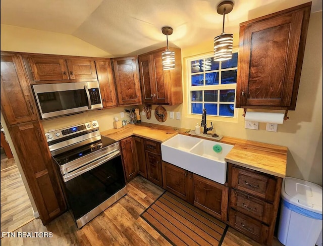 kitchen with electric range oven, lofted ceiling, light hardwood / wood-style floors, sink, and hanging light fixtures