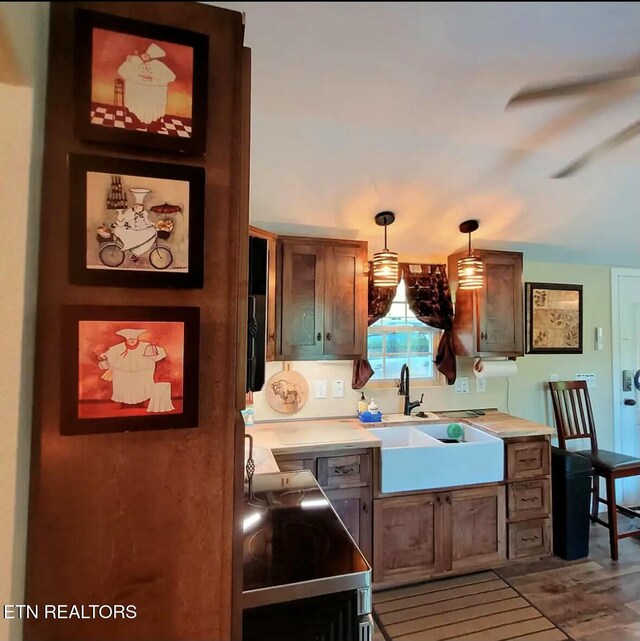 kitchen with wood-type flooring, sink, hanging light fixtures, ceiling fan, and stove