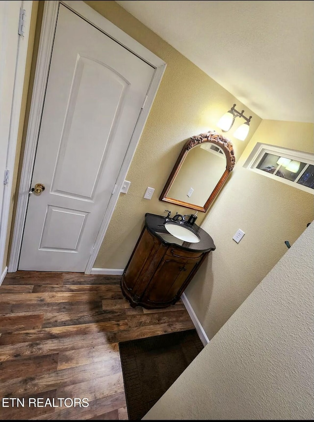 bathroom with vanity, lofted ceiling, and wood-type flooring