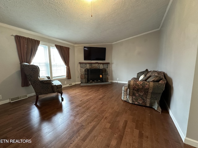 living area with hardwood / wood-style flooring, a stone fireplace, ornamental molding, and a textured ceiling