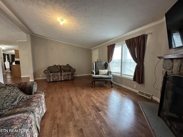 living room with hardwood / wood-style flooring, a textured ceiling, crown molding, and a fireplace