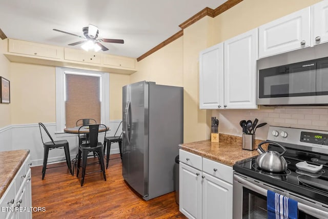 kitchen featuring ornamental molding, stainless steel appliances, ceiling fan, white cabinets, and dark hardwood / wood-style floors