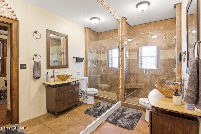 bathroom featuring tile patterned floors, vanity, toilet, and a shower with door