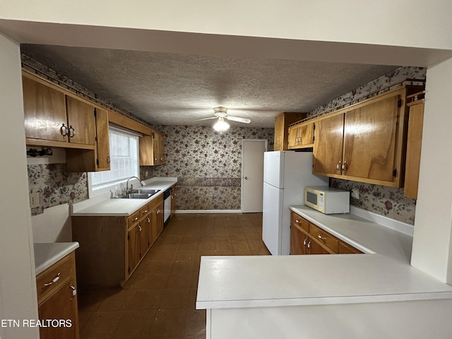 kitchen with ceiling fan, sink, stainless steel dishwasher, kitchen peninsula, and a textured ceiling