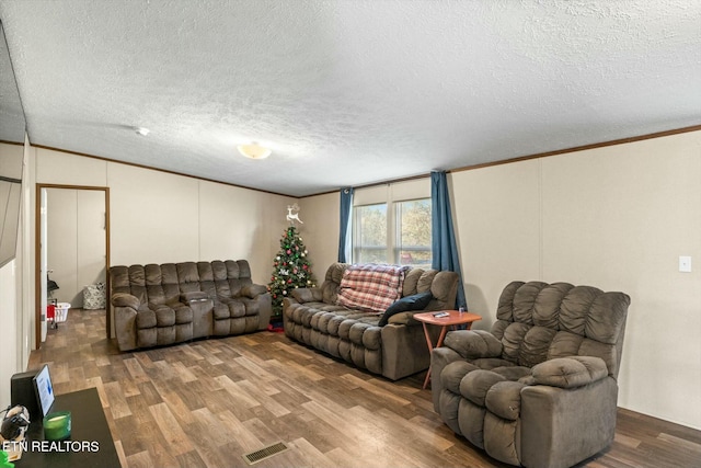 living room with a textured ceiling, hardwood / wood-style flooring, vaulted ceiling, and ornamental molding