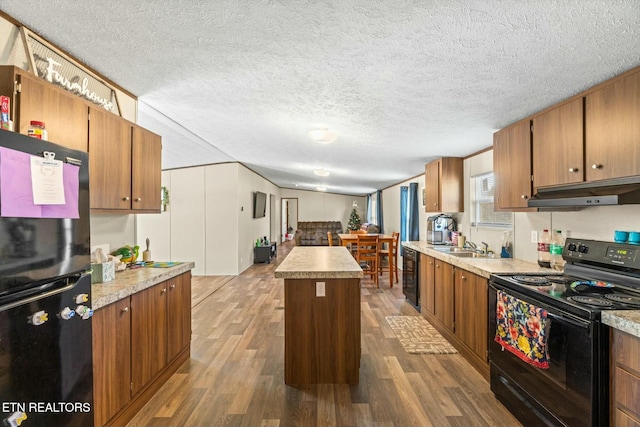 kitchen featuring beverage cooler, dark wood-type flooring, sink, black appliances, and a center island