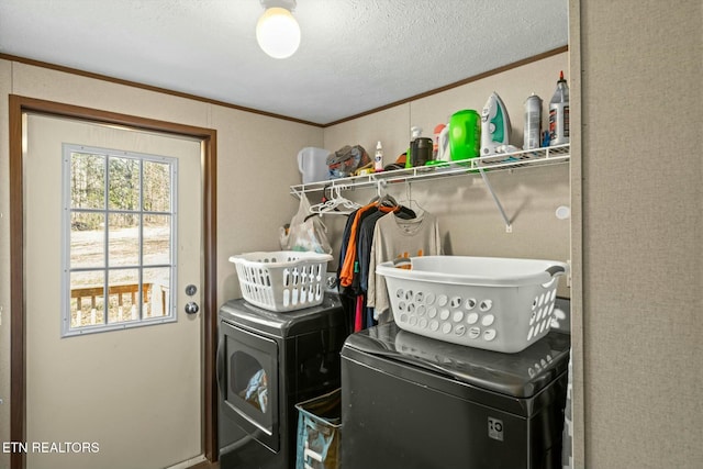 laundry room with a textured ceiling, ornamental molding, and washing machine and clothes dryer