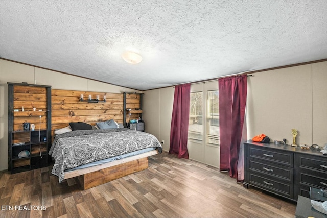 bedroom featuring wood-type flooring, a textured ceiling, and vaulted ceiling