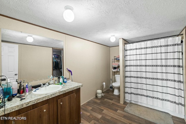 bathroom with hardwood / wood-style floors, vanity, toilet, a textured ceiling, and curtained shower