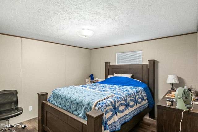 bedroom with a textured ceiling, ornamental molding, and dark wood-type flooring