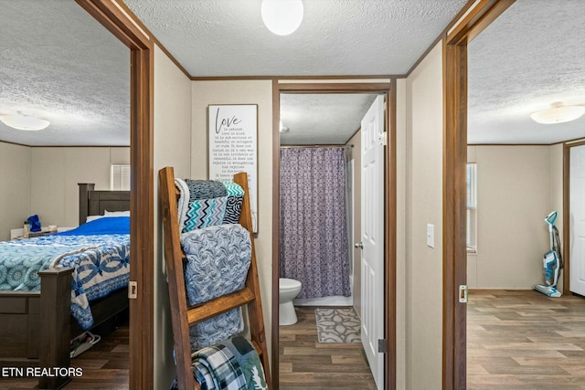 bedroom with hardwood / wood-style floors, connected bathroom, and a textured ceiling