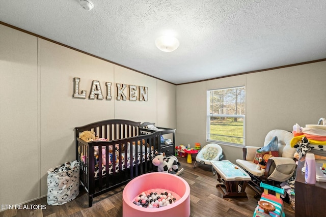 bedroom featuring dark hardwood / wood-style flooring, a crib, and ornamental molding