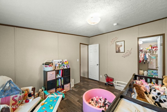 rec room with a textured ceiling, dark hardwood / wood-style flooring, and crown molding