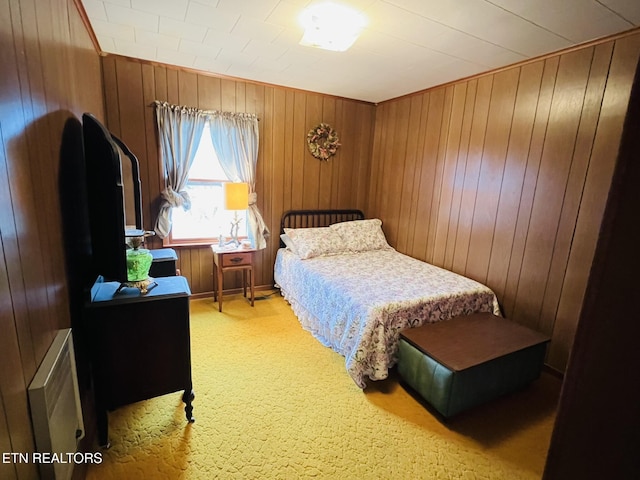 bedroom featuring light colored carpet and wooden walls