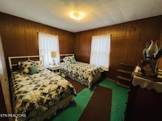 bedroom with dark carpet and wood walls