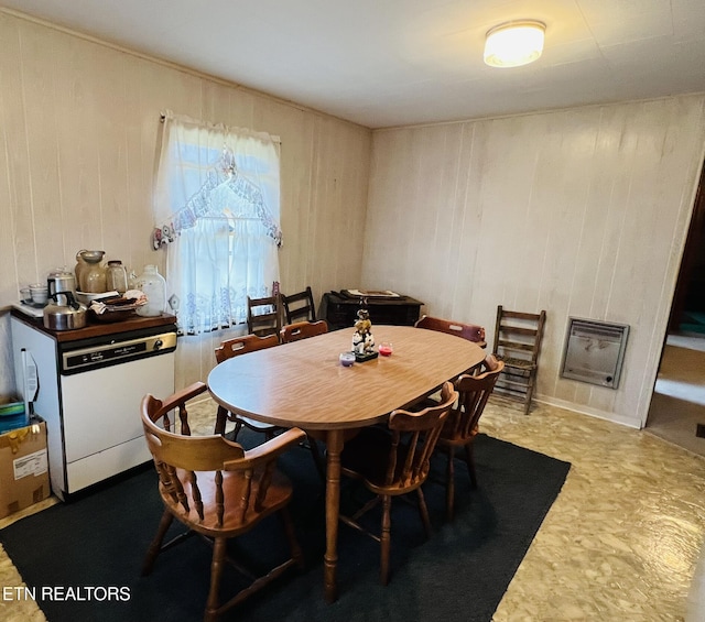 dining room featuring heating unit and wooden walls