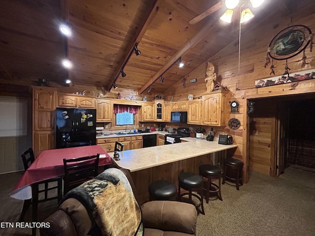 kitchen with kitchen peninsula, rail lighting, wooden walls, black appliances, and lofted ceiling with beams