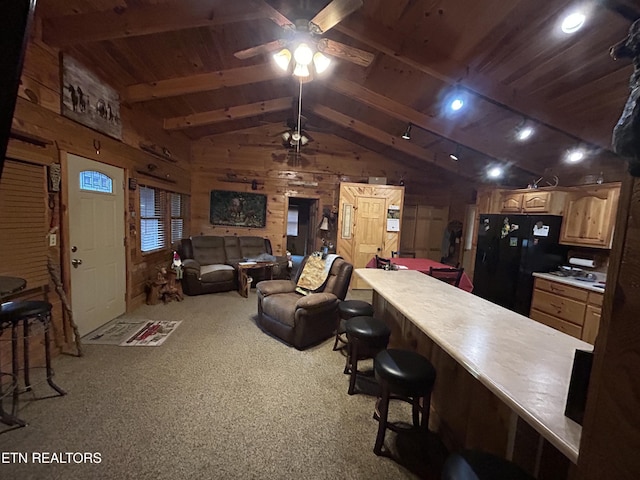 carpeted living room with vaulted ceiling with beams, wood walls, wooden ceiling, and ceiling fan