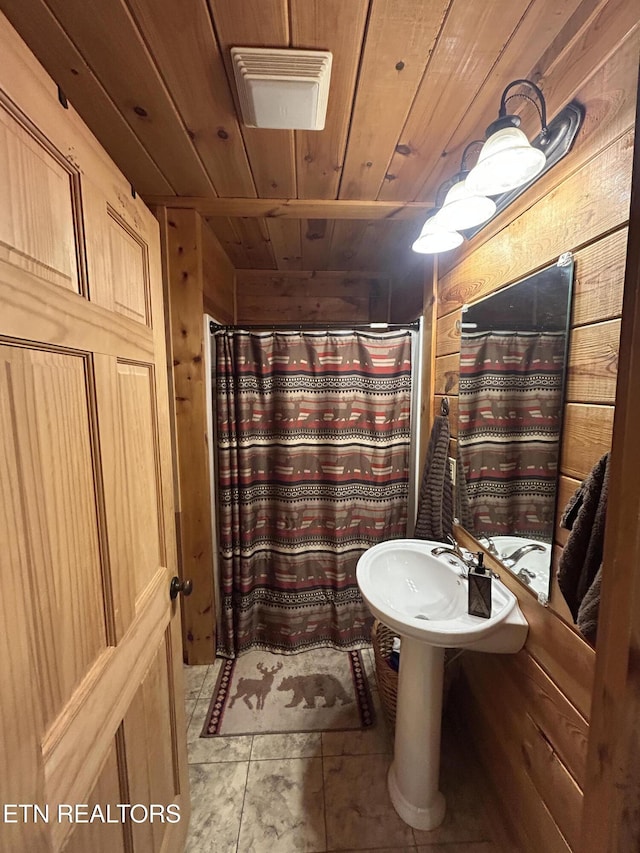 bathroom with tile patterned flooring, wooden ceiling, and wood walls