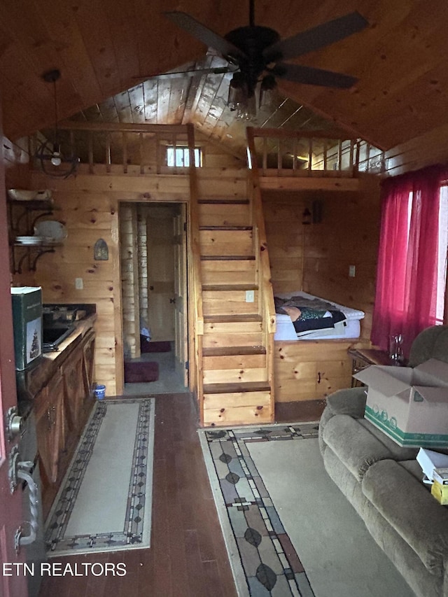 interior space with ceiling fan, a healthy amount of sunlight, dark wood-type flooring, lofted ceiling, and wood walls