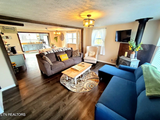 living room featuring a wood stove, a chandelier, a textured ceiling, and hardwood / wood-style flooring