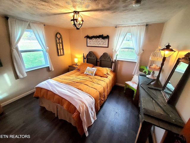 bedroom with dark hardwood / wood-style floors, a textured ceiling, and multiple windows