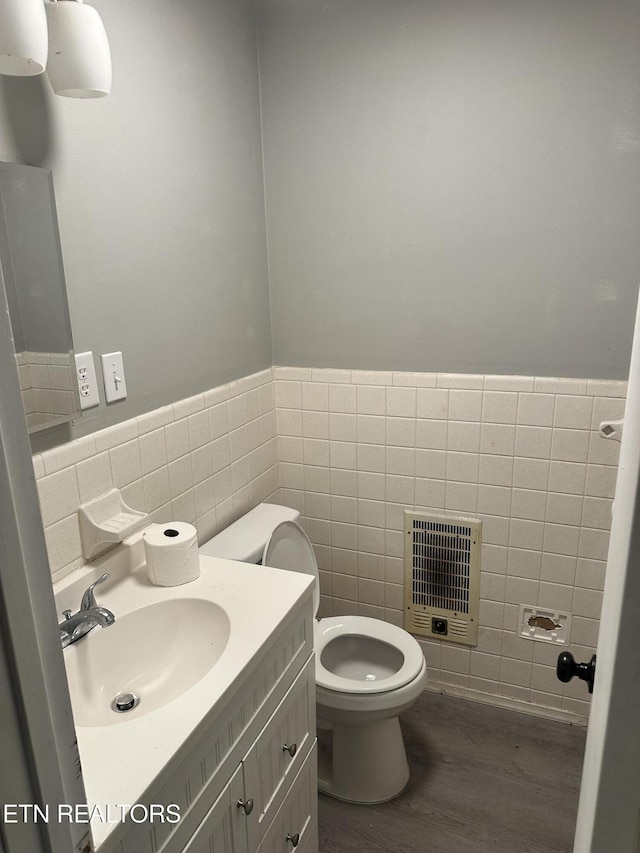 bathroom with vanity, heating unit, tile walls, hardwood / wood-style floors, and toilet