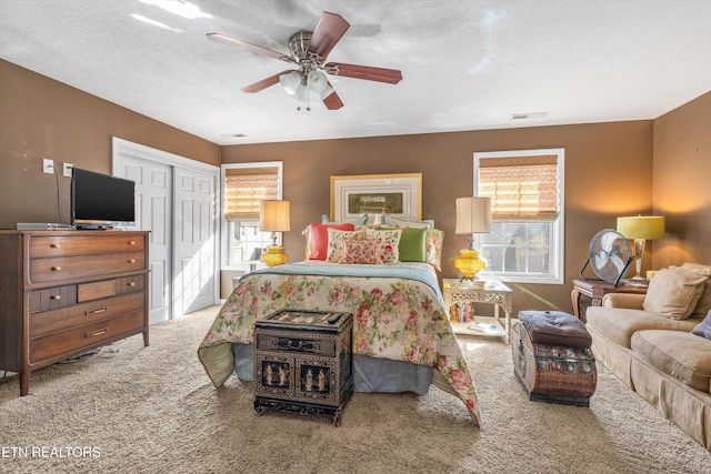 carpeted bedroom featuring ceiling fan, a closet, and a textured ceiling