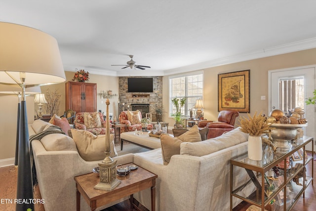 living room with dark wood-type flooring, ceiling fan, a fireplace, and crown molding