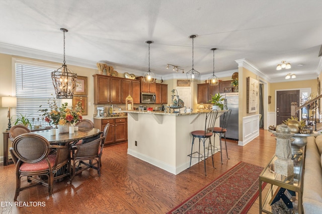 kitchen featuring stainless steel appliances, hanging light fixtures, a center island, and a breakfast bar area