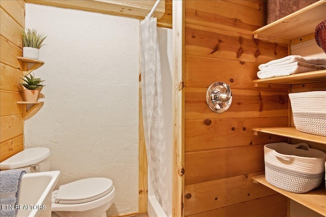 bathroom with toilet, walk in shower, and wood walls