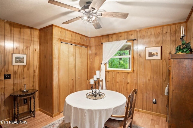 dining space featuring light hardwood / wood-style flooring, ceiling fan, and wood walls