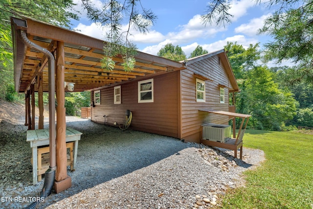 view of side of home with central AC unit and a yard