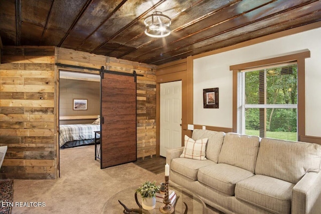 carpeted living room with a barn door, wood walls, and wood ceiling