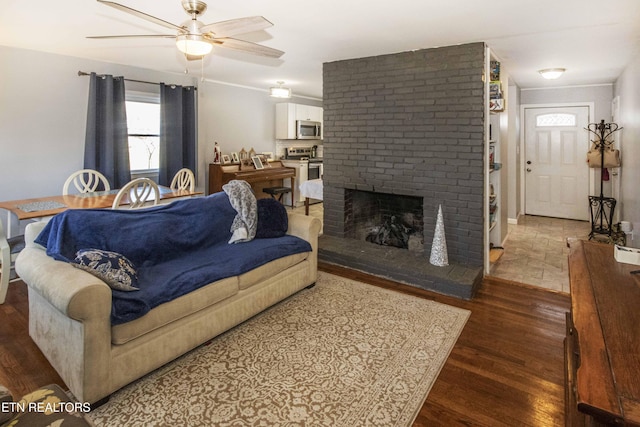 living room with ceiling fan, dark hardwood / wood-style floors, and a brick fireplace