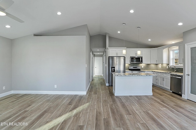 kitchen featuring appliances with stainless steel finishes, tasteful backsplash, decorative light fixtures, white cabinets, and a center island