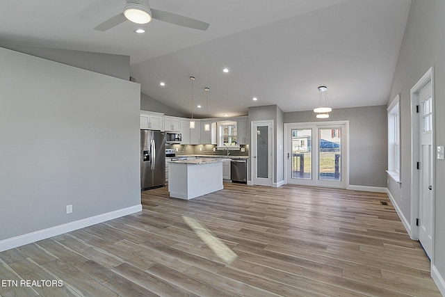 kitchen featuring appliances with stainless steel finishes, backsplash, a kitchen island, white cabinetry, and hanging light fixtures