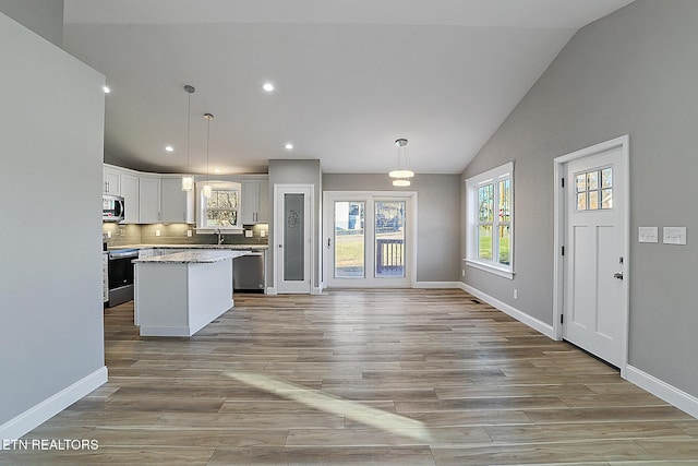 kitchen featuring white cabinets, stainless steel appliances, a kitchen island, and hanging light fixtures